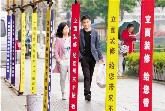 近日，杭州火车东站附近的天成路沿街，多处迎G20杭州峰会外立面装修施工现场，脚手架贴上了五颜六色的标语，上面写着：“立面装修，给您带来不便，敬请谅解。”让行人感到路边施工的文明。 本报记者 吴煌 摄