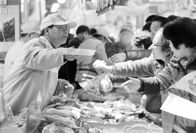 “北大才子屠夫”陆步轩（左）在超市挥刀斩肉，手法娴熟。 